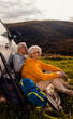 © Zoran Zeremski - Senior couple sitting against the car, resting after hiking in countryside.