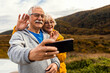 © Zoran Zeremski - Senior couple esting after hiking in countryside making selfie with smartphone.