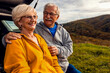 © Zoran Zeremski - Senior couple sitting against the car, resting after hiking in countryside.
