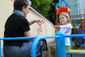 Sticker - Sign language communication with a deaf child on a playground.