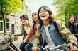 © Jasmina - Happy group of young Japanese people with backpack riding a bike in Amsterdam. Life style concept with friends having fun together on summer holiday