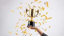 Close-up Of Business Person Hand Holding And Celebrating Success With Golden Trophy Award On Isolated White Background. Generative AI