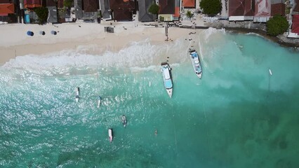 Wall Mural - Aerial shoreline view of Jungut Batu Village at Nusa Lembongan with tourist speedboats anchored along the beach. One of travel destinations close to Bali island, Indonesia. 4K drone footage video