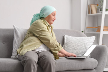 Wall Mural - Senior woman after chemotherapy using laptop at home