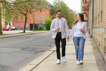 Beautiful loving happy couple drinking coffee and walking in city on spring day