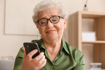 Poster - Senior woman using mobile phone at home, closeup