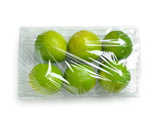 Wall Mural - Fresh limes in plastic food wrap on white background