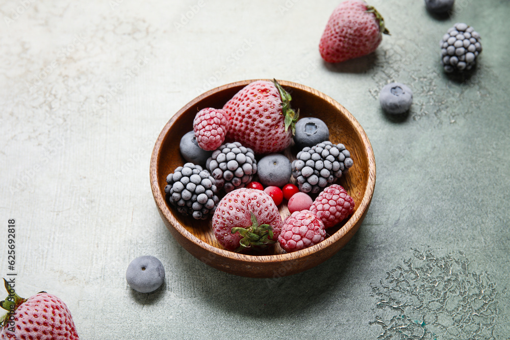 Bowl of frozen berries on grey grunge background