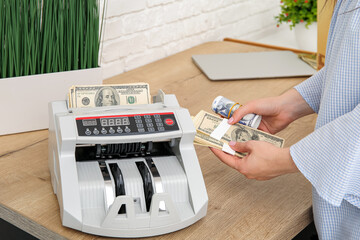 Woman counting money near cash register on table in office, closeup