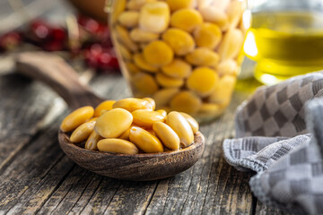 Sticker - Lupini beans in brine. Pickled lupin in spoon on wooden table.