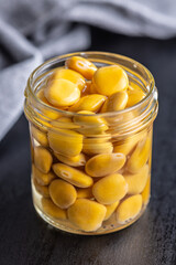 Sticker - Lupini beans in brine. Pickled lupin in jar on black table.