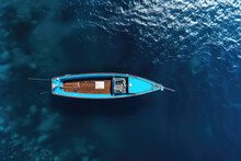 An Overhead View Of The Sea Blue With A Small Two-seater Boat In Sunny Day. Creative Nautical Wallpaper. Minimalist Style. Clear Blue Water With Little Waves.