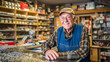 © wetzkaz - elderly man is shopkeeper of a local small business selling goods or services, fictional location