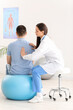 © Pixel-Shot - Female doctor checking posture of young man in clinic