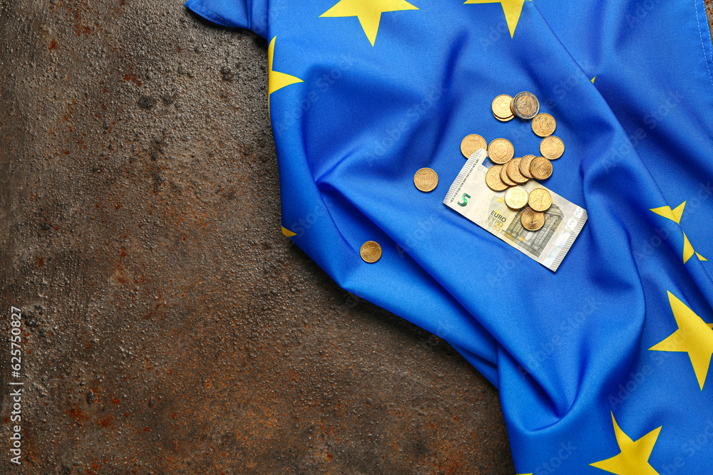 Banknotes, coins and European Union flag on brown background