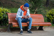 © DimaBerlin - Upset young guy sitting alone on bench in park with smartphone in hands and reads bad news. Receives not good text messages, breaks up with girl on phone, feels sad and heartbroken