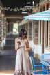 © travnikovstudio - Beautiful woman in dress in a cafe outdoor. Happy tourist at open air restaurant with her smartphone.