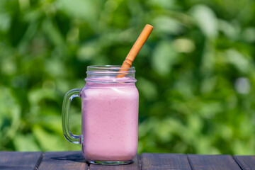 Wall Mural - Fresh chilled strawberry smoothie in a glass mug on a wooden table on a sunny summer day, closeup. Refreshing summer fruit drink. The concept of healthy eating