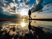 A Man Silhouette Is Shown Walking Under Stormy Clouds, Reflecting On Water,