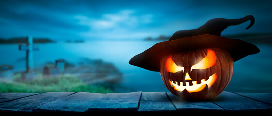 Wall Mural - the spooky haunted evil glowing eyes of jack o' lanterns, halloween pumpkin, on the right of a woode