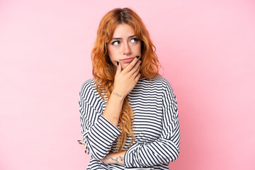 Wall Mural - Young caucasian woman isolated on pink background having doubts and with confuse face expression