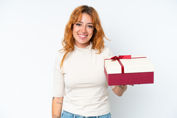 Young caucasian woman holding a gift iso0lated on white background smiling a lot