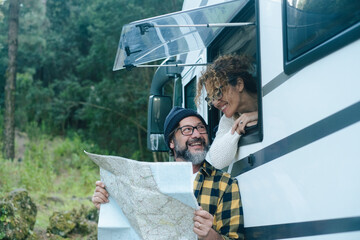 Wall Mural - Happy mature couple enjoy vanlife camper vacation travel lifestyle talking and looking together a map guide to choose next holiday destination. Man outside and woman at the window. Motorhome vehicle