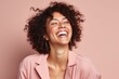 © igolaizola - Portrait of a beautiful young african american woman laughing against pink background