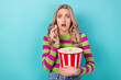 Portrait of impressed speechless girl with wavy hairdo wear stylish clothes hold popcorn at cinema isolated on blue color background