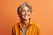 © igolaizola - Portrait of a smiling senior woman looking at camera isolated over orange background