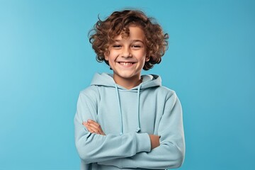 Portrait of a smiling little boy in a blue hoodie on a blue background