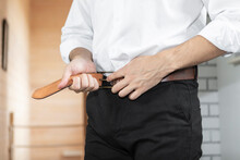 Young Businessman Wearing Pant Belt In The Room, Close-up Photo. Preparation For New Busy Day