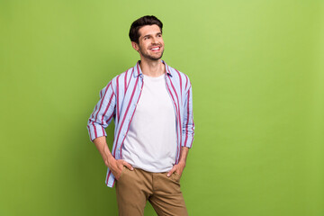 Sticker - Photo of confident man with stylish haircut dressed striped shirt arms in pockets look empty space isolated on green color background