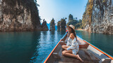 Fototapeta  - Traveler asian woman relax and travel on Thai longtail boat in Ratchaprapha Dam at Khao Sok National Park Surat Thani Thailand