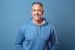 © igolaizola - Portrait of handsome mature man smiling at camera while standing against blue background