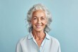 Portrait of smiling senior woman with grey hair isolated on blue background