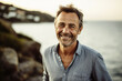 Lifestyle portrait of a grinning middle age man enjoying  a walk at sea, landscape background