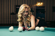 Blond woman playing enjoying billiard, hold billiard balls on table with green surface in billiard club. Pool game snooker pyramid player

