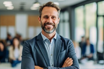 Wall Mural - Portrait of smiling mature businessman standing with arms crossed in modern office