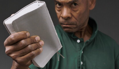 man praying to god holding bible with hands together on grey background with people stock photo	