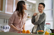 happy young asian couple conversing while preparing food in kitchen at home