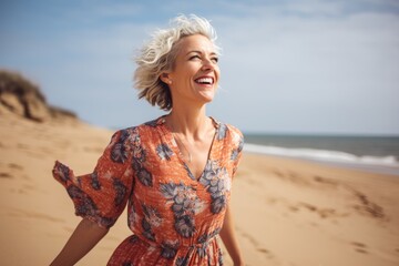 Wall Mural - Portrait of happy mature woman standing on sandy beach and looking away