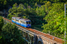 Historic Electric Train On Famous Steel Bridge In Intragna In Centovalli Valley. Famous Narrow Gauge Railway Line From Locarno To Domodossola In Italy In The Swiss Alps. Popular Tourist Train Journey.