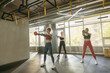 © Daria - Group of sporty strong women doing squats with weights in their hands in modern sports club