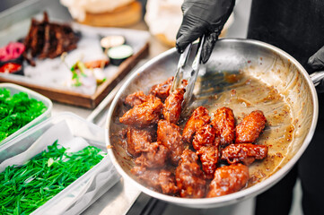 Wall Mural - woman chef cooking chicken wings in a sauce in the kitchen