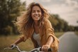 © igolaizola - smiling young woman riding bicycle on road in park during summer day