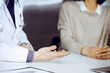 © rogerphoto - Unknown male doctor and patient woman discussing something while sitting in clinic. Best medical service in hospital, medicine, pandemic stop