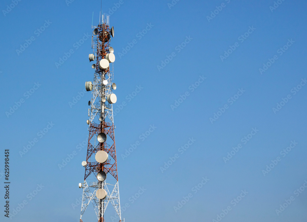 Telecommunications towers and telecommunication networks, satellite dishes against blue sky.