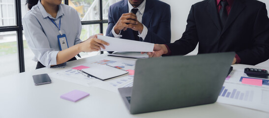 Business documents on office table with smart phone and calculator digital tablet and graph business with social network diagram and two colleagues discussing data working in office