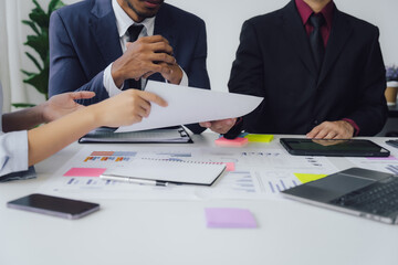 Business documents on office table with smart phone and calculator digital tablet and graph business with social network diagram and two colleagues discussing data working in office